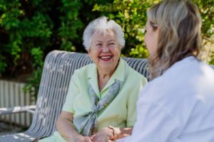 Seniorin lacht fröhlich auf einer Parkbank